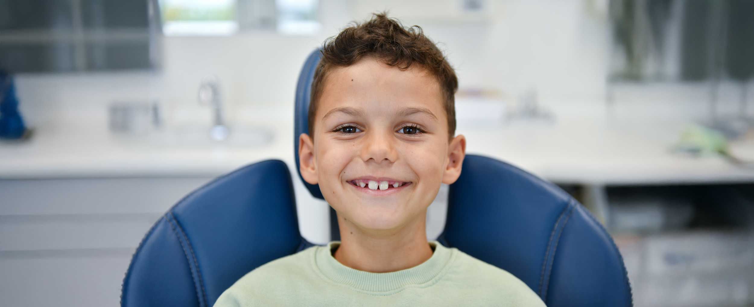 Kleiner Junge lacht in die Kamera und zeigt seine Kinderzähne